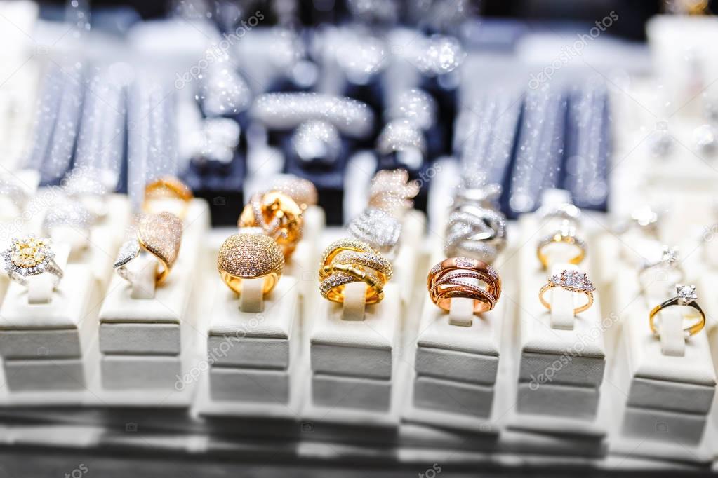 Various Golden rings with precious gems in jewelry shop, window close-up