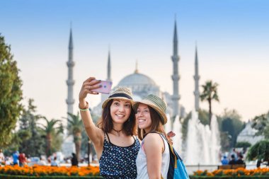 İki gülümseyen kız arkadaşları ile akıllı telefon selfie Istanbul'da Sultanahmet Camii önünde yapıyor. Seyahat ve tatil Türkiye kavram
