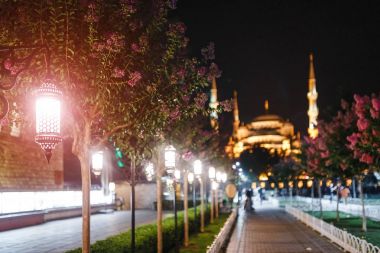 Arapça tarzı fenerler ve ünlü Sultanahmet Camii görkemli silueti ile aydınlatılmış Istanbul tarihi merkezinde, gece, güzel bir sokakta