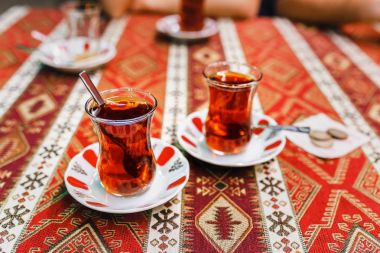 Lezzetli kırmızı çay ile geleneksel armut close-Up etnik desenli masa örtüsü kafede cam şeklinde