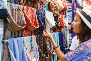 Genç kadın alışveriş için A yeni atkı ve bazar seçerek renkli kumaş