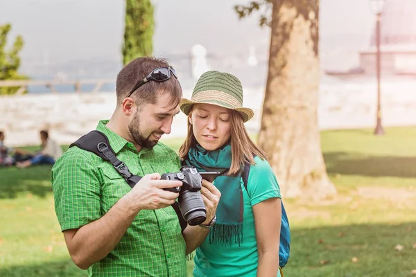 Un par de turistas revisando fotos en una cámara dslr en el parque, aprendiendo foto juntos concepto — Foto de Stock