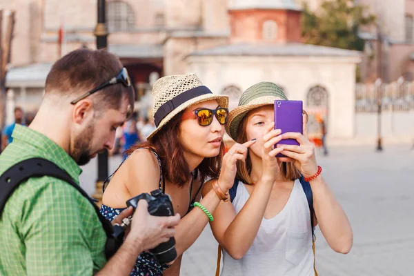 Молоді друзі у подорожі фотографують місто і вивчають мобільні фотографії — стокове фото