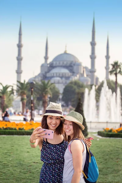 Dos novias sonrientes con teléfono inteligente haciendo selfie frente a la Mezquita Azul en Estambul. Viajes y vacaciones en Turquía concepto — Foto de Stock