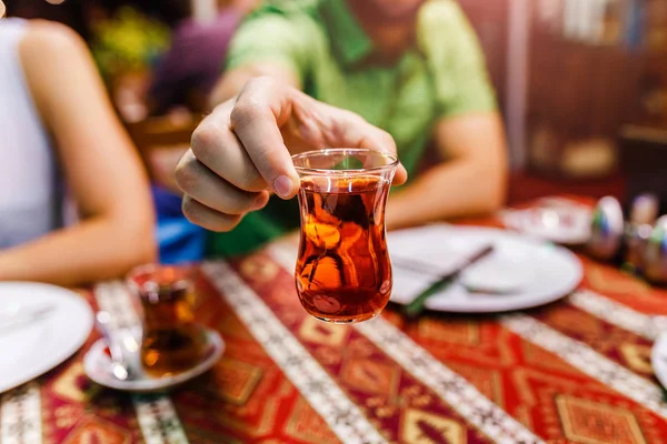 Close-Up of delicious Red Turkish tea with traditional pear shaped glass on ethno patterned tablecloth in cafe