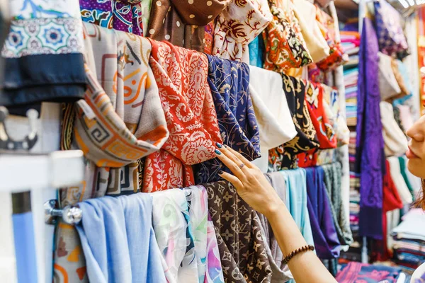 Молодая женщина покупает новый шарф и выбирает красочную ткань на базаре — стоковое фото
