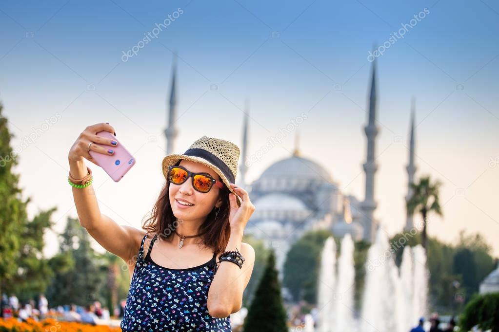 Happy woman in hat and sunglasses making selfie by the smartphone on the background of the Blue Mosque, Istanbul, Travel and vacation in Turkey concept