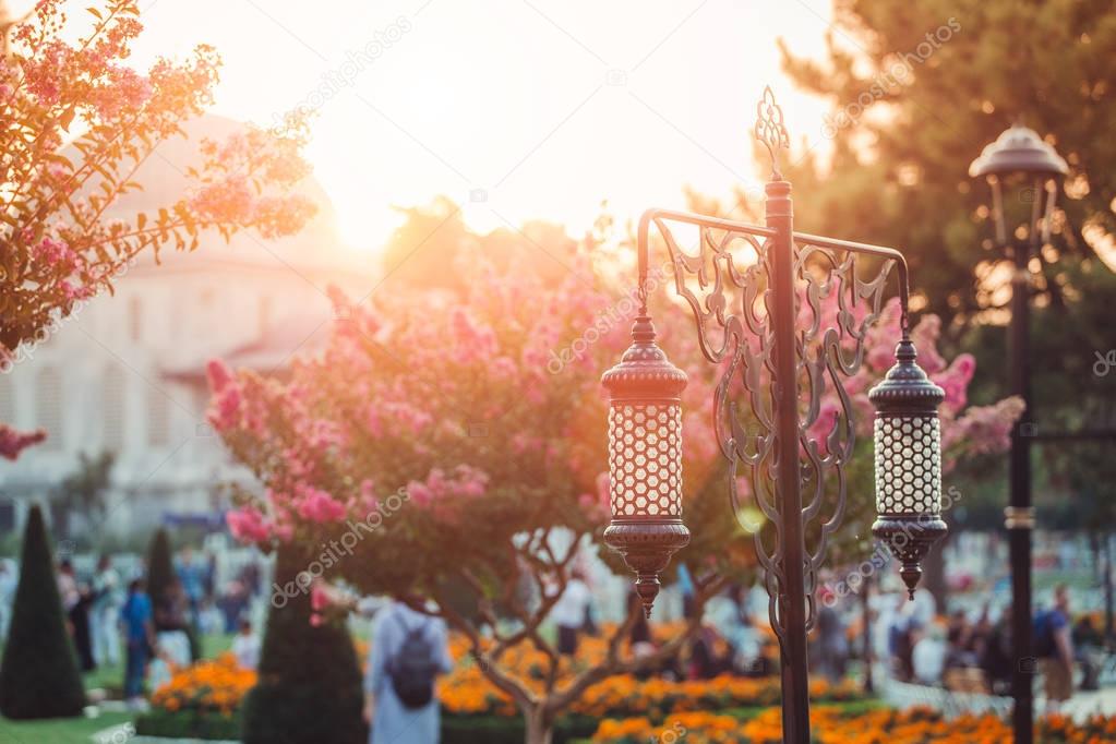 Traditional islamic ramadan lantern and blooming trees in park at Sultan Ahmet square near Blue Mosque in Istanbul, Turkey