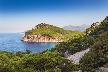 Pastoral Akdeniz peyzaj cennet kavramı ile yalnız bay masmavi renk ve çam ormanları ile kaplı dağları, seyahat