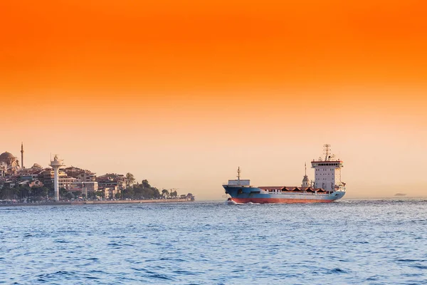 Empty container cargo ship in Istanbul Bosporus harbor at sunset