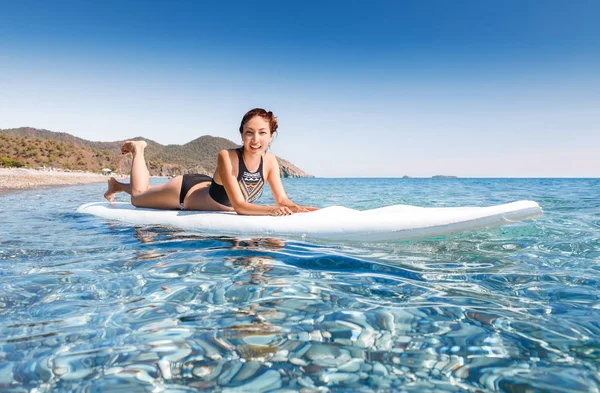 Mladá krásná žena, relaxační, ležící v modré moře na palubě sup v blízkosti Chirali beach, Turecko — Stock fotografie