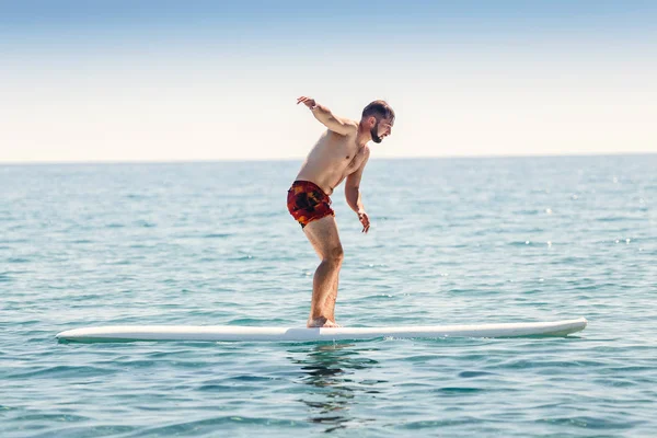Hombre principiante tratar de surfear en una tabla en un mar cerca de la costa — Foto de Stock
