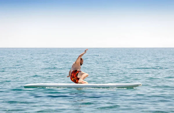 Beginnende surfer beginner valt van de Raad van bestuur tijdens de training in de zee — Stockfoto