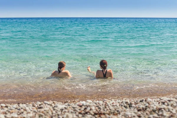 Vista trasera de dos amigas nadando en un mar y hablando — Foto de Stock
