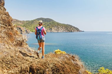 Genç kadın Gezgin Cliff'in kenarında duran ve bir Akdeniz manzarası, yaz tatil kavramı seyir sırt çantası ile