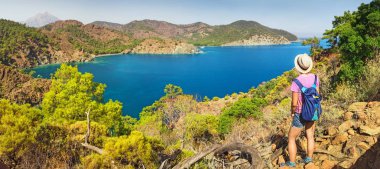 Genç kadın Gezgin Cliff'in kenarında duran ve bir Akdeniz manzarası, yaz tatil kavramı seyir sırt çantası ile