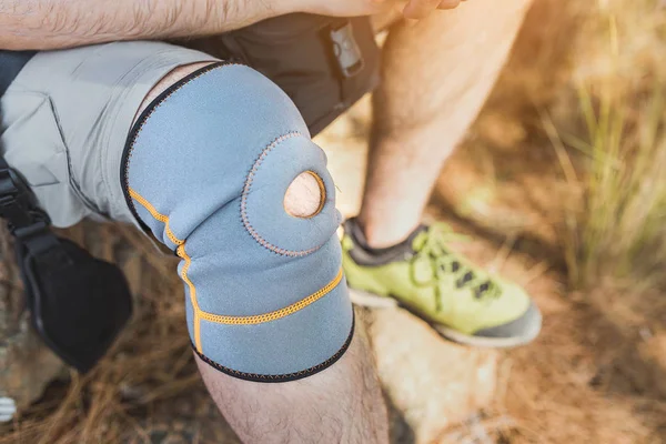 close up of knee support brace on leg of a traveler man during hiking outdoors in nature