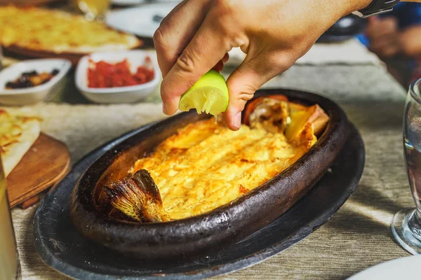 Appetizing baked hot fish freshwater trout entirely in a dish on a table in a restaurant with fresh lemon or lime — Stock Photo, Image