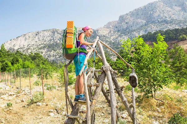 Tourists with a large backpack are climbing through the village fence while traveling along the Lycian Way in the background of Mount Tahtali, Turkey — Stock Photo, Image