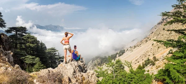 Due donne stanno in cima alla montagna sopra le nuvole e la nebbia e sono felici dalla vista pottering delle montagne del Toro vicino alla vetta di Tahtali, Via Licia — Foto Stock