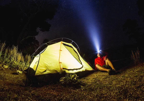 Man hiker with flashlight near his camp tent at night in fog — Stock Photo, Image