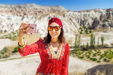 Bir turist Doğu Asya kız telefonda güzel Vadisi Kapadokya Türkiye'de bir fotoğraf yapar.