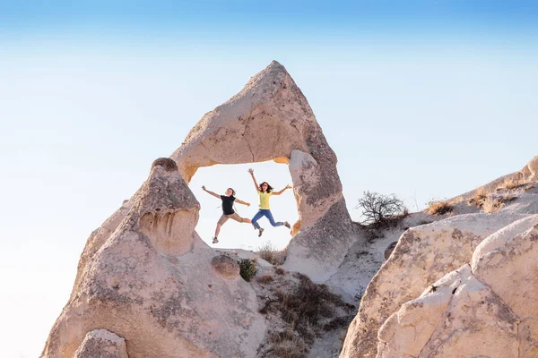 Happy Friends hoppa och ha roligt i en sten arch i Göreme nationalpark i Cappadocia fechimneys på sommaren i Turkiet — Stockfoto