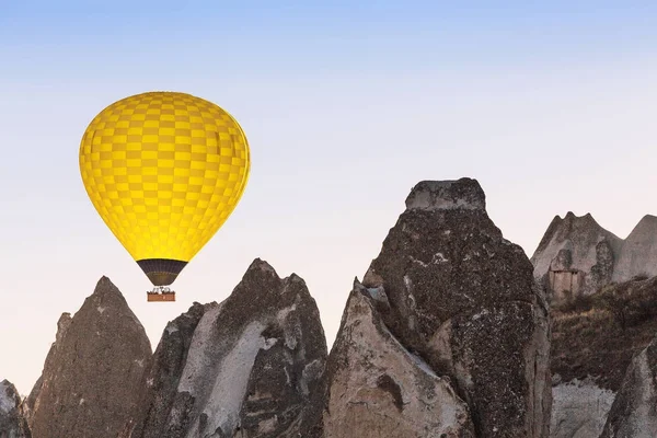 Globo de aire caliente volando sobre la ciudad cueva y acantilados rocosos de Capadocia, una de las principales atracciones turísticas de Turquía al atardecer —  Fotos de Stock