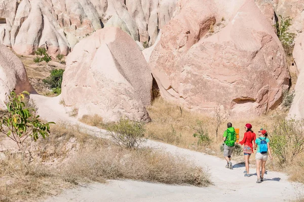 Un grupo de jóvenes viajeros activos y brillantes caminan entre las coloridas colinas del desierto de la toba en el parque nacional de Capadocia, Turquía — Foto de Stock