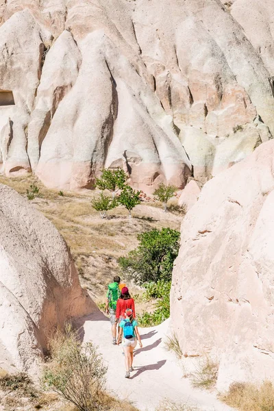 Un grupo de jóvenes viajeros activos y brillantes caminan entre las coloridas colinas del desierto de la toba en el parque nacional de Capadocia, Turquía — Foto de Stock