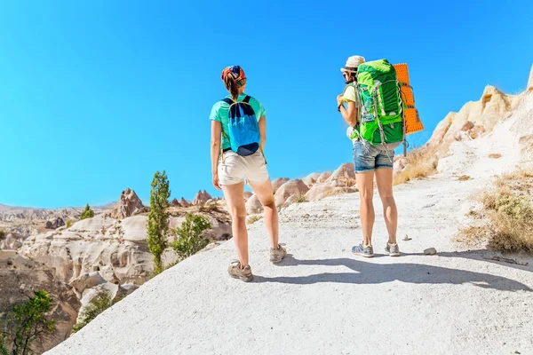 Two happy active women hiking together in a rock sandstone canyon in the desert, travel and outdoor vacation concept — Stock Photo, Image