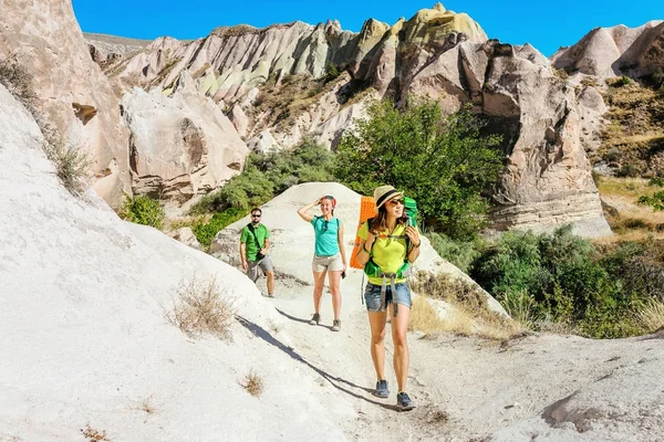 Un grupo de jóvenes viajeros activos y brillantes caminan entre las coloridas colinas del desierto de la toba en el parque nacional de Capadocia, Turquía — Foto de Stock