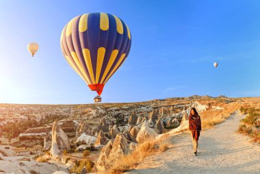 Bir turist kız harika manzarayı gündoğumu ve Kapadokya balon dağın tepesinde. Türkiye'de kavram mutlu seyahat
