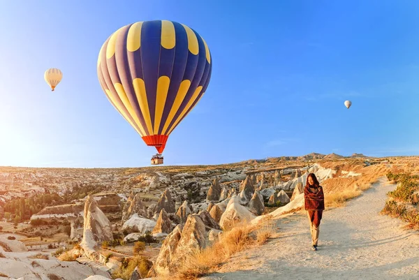 Een toeristische meisje op een bergtop genieten van prachtig uitzicht op de zonsopgang en ballonnen in Cappadocië. Gelukkig reizen in Turkije concept — Stockfoto