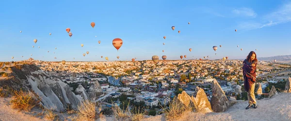 Ein Touristenmädchen auf einem Berggipfel, das einen wunderbaren Blick auf den Sonnenaufgang und Luftballons in Kappadokien genießt. Glückliches Reisen in der Türkei — Stockfoto