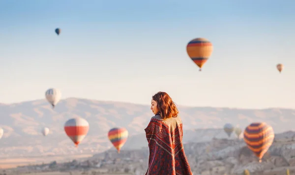 En turist flicka på en bergstopp som njuter av underbar utsikt över soluppgången och ballonger i Kappadokien. Lycklig resa i Turkiet koncept — Stockfoto