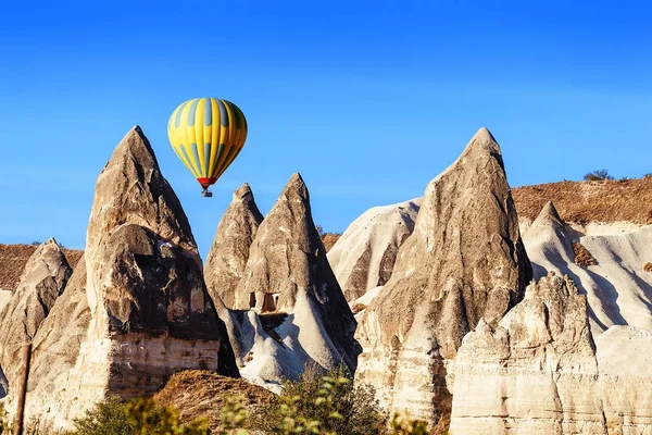 Balão de ar quente colorido voando sobre a paisagem rochosa na Capadócia Turquia — Fotografia de Stock