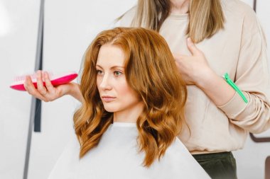 Genç güzel güzellik salonunda bir tarak tutarak onun Kuaför professional ile saç şekillendirme tartışıyor kadın zencefil