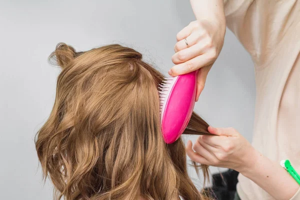 Перукар готує до імбирної жінки в салоні краси, розчісуючи волосся пензлем — стокове фото