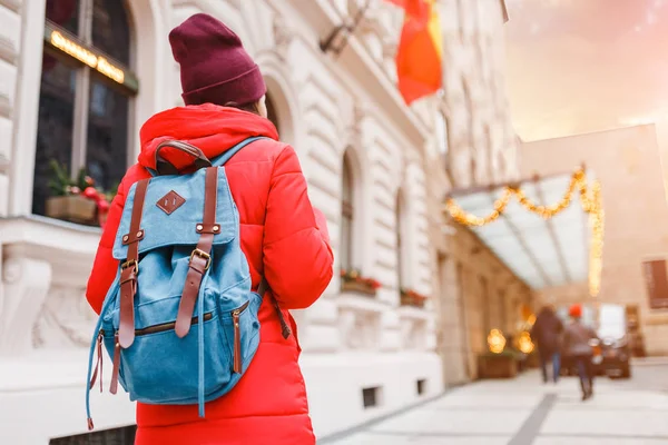 Menina turística com mochila de pé perto da decoração de Natal na entrada de um hotel, viajar no conceito de Ano Novo — Fotografia de Stock