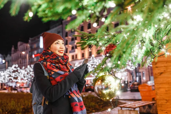 Woman tourist at night admiring the Christmas tree with lights in the main square of the European city on New Years Eve — Stock Photo, Image