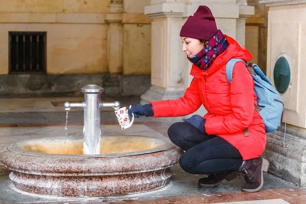 O femeie turistică bea apă dintr-un izvor termic medicinal din Karlovy Vary, Republica Cehă — Fotografie, imagine de stoc