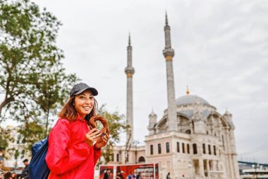 Istanbul, Türkiye'de Ortaköy Camii arka plan üzerinde simit yiyen genç kadın