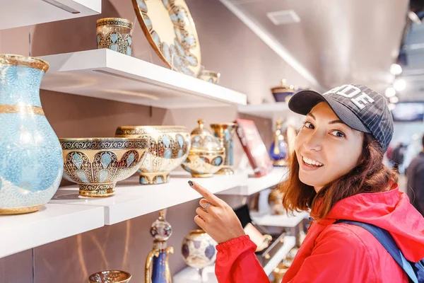 Mulher turística escolhendo pratos de cerâmica ornamental na loja de souvenirs — Fotografia de Stock