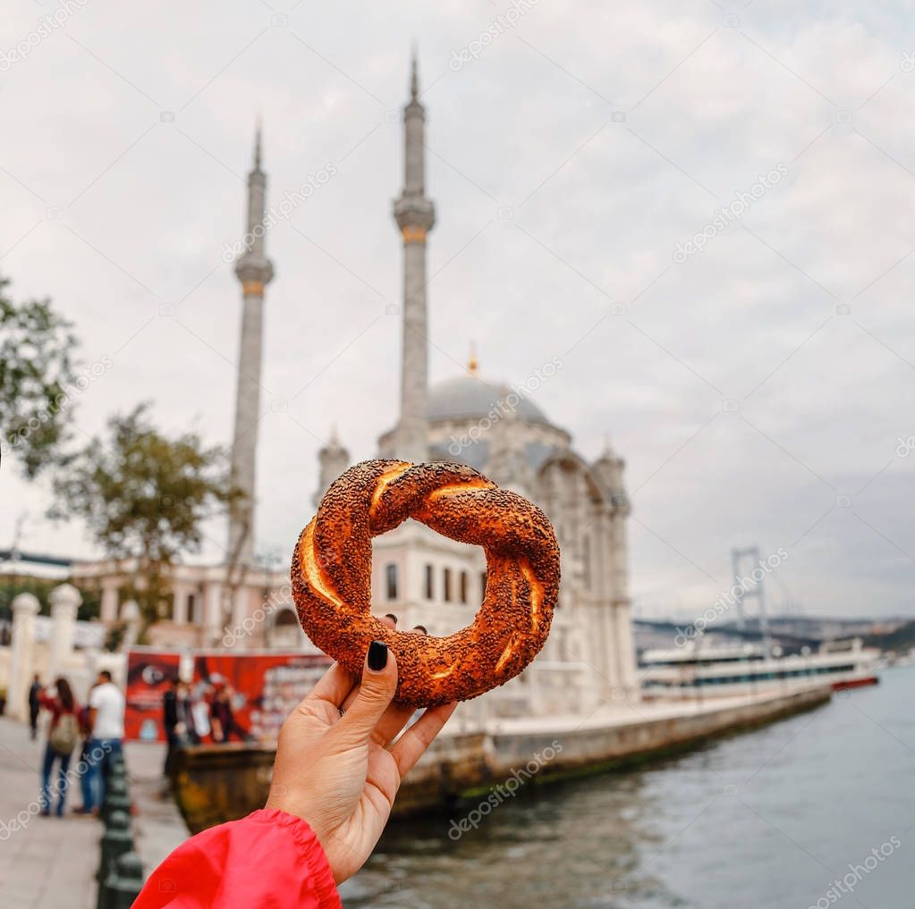 Holding turkish simit with Ortakoy Mosque on background