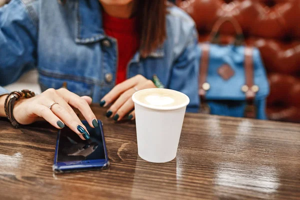 Retrato de estilo de vida de una mujer bebiendo café y mensajes de texto en un teléfono inteligente — Foto de Stock