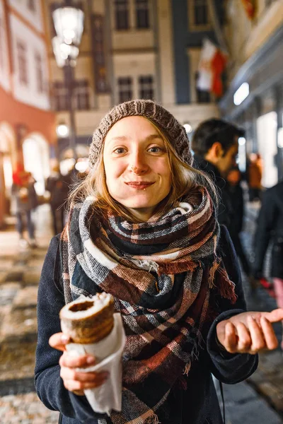 Szczęśliwy, że kobieta zjada tradycyjne czeskie wypieki słodkie zabawa o nazwie Trdelnik lub Trdlo w Pradze street w czasie zimy — Zdjęcie stockowe