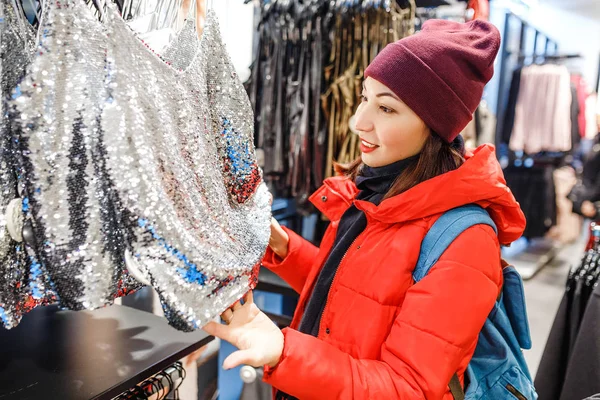 Счастливая женщина покупает зимнюю одежду в магазине, охотясь за продажами — стоковое фото