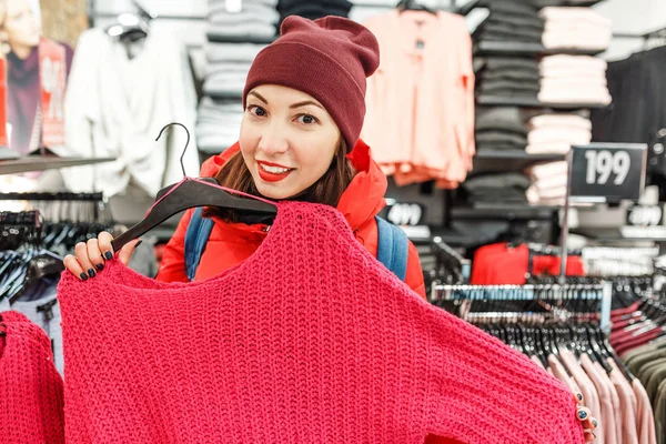Счастливая женщина покупает зимнюю одежду в магазине, охотясь за продажами — стоковое фото