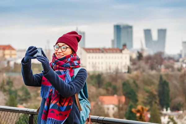 Genç kadın selfie fotoğraf telefon ile Prag güzel cityscape arka plan üzerinde kış anda yapma. — Stok fotoğraf